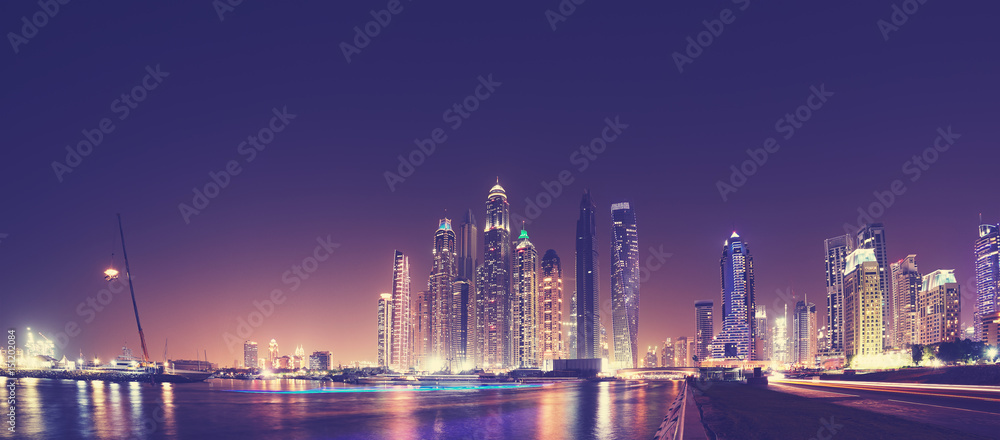 Fototapeta premium Fisheye lens panoramic picture of Dubai waterfront skyline at night, color toning applied, United Arab Emirates.