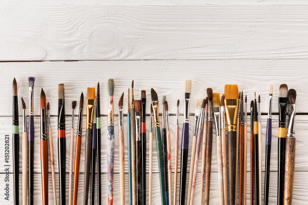 Close-up top view of various paintbrushes collection on wooden table Close-up top view of various paintbrushes collection on wooden table