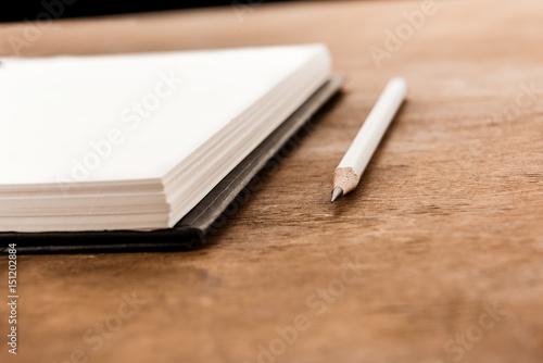 Close-up view of pencil and empty notebook on wooden table