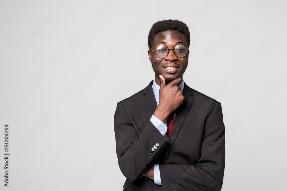Thinking about new solutions. Handsome young African man holding hand on chin and looking on camera with smile on grey Thinking about new solutions. Handsome young African man holding hand on chin and looking on camera with smile on grey