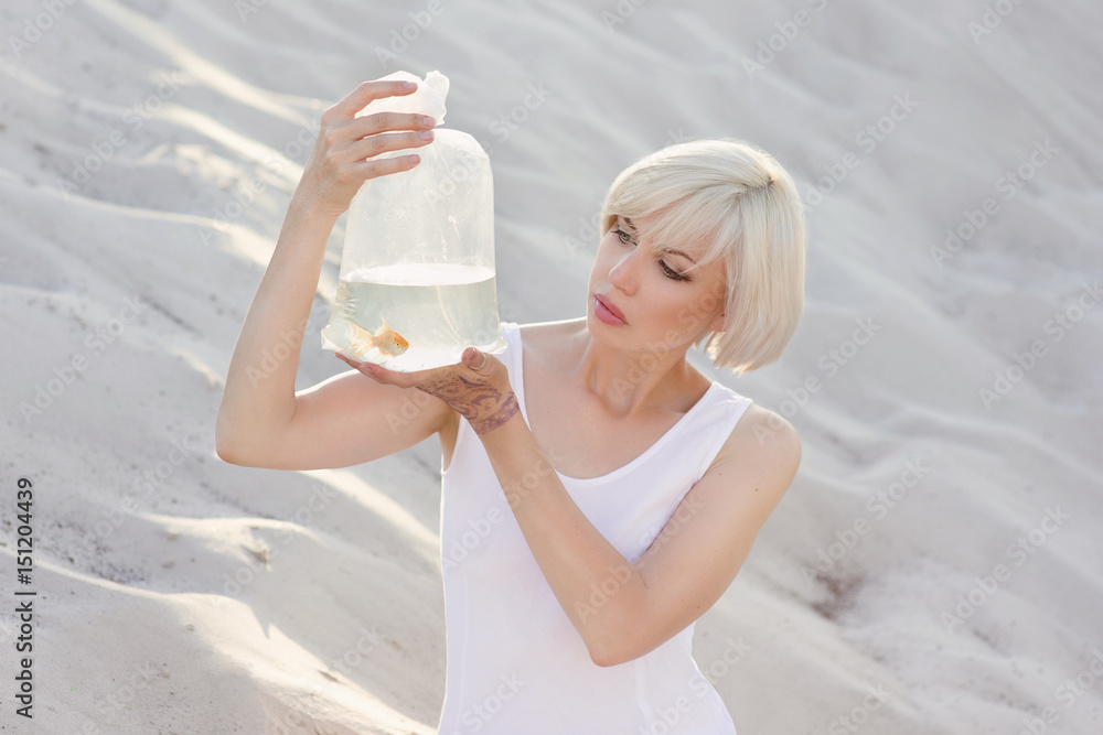 Young tender beautiful blonde woman in the desert with goldfish in her hands Young tender beautiful blonde woman in the desert with goldfish in her hands