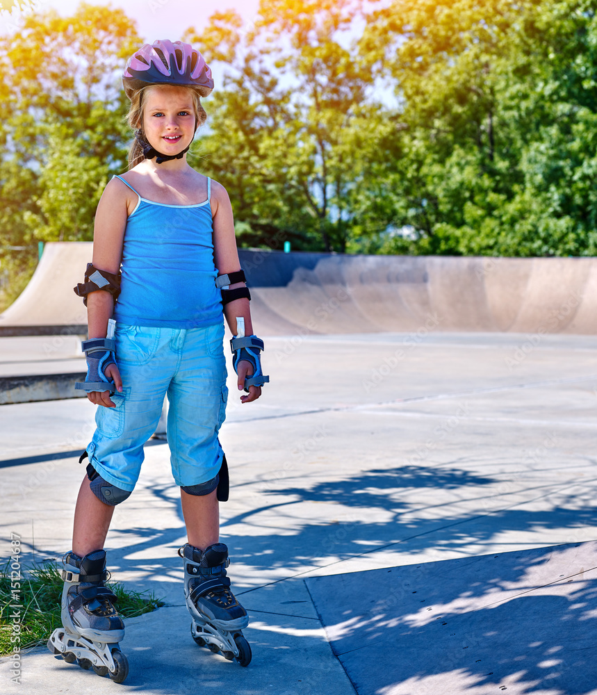 Girl roller in skates park. Child wear safety helmet do sport exercise