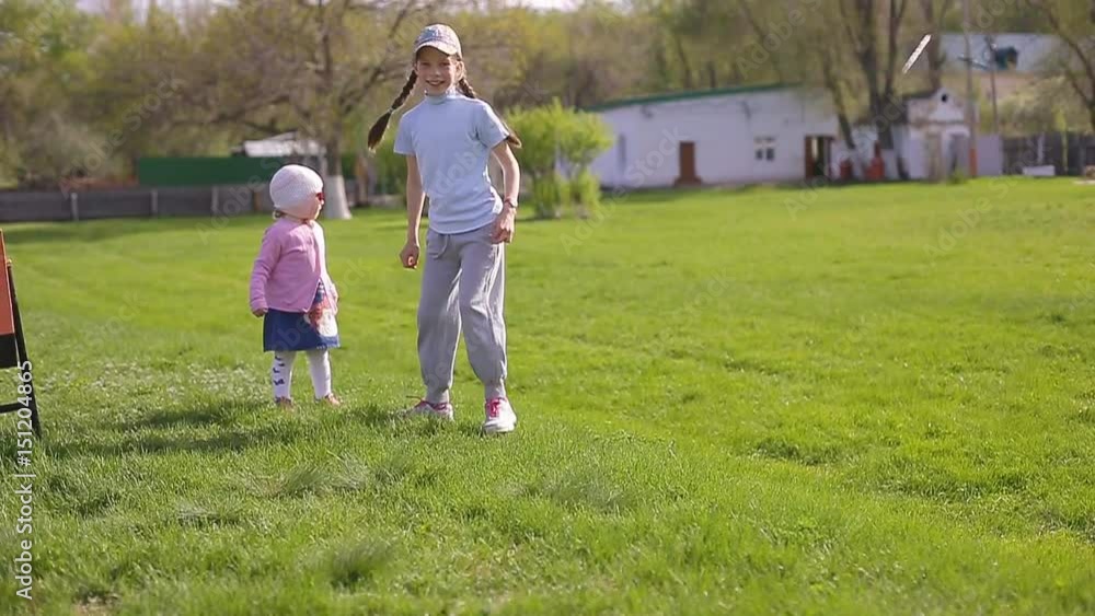 Two sisters play and run around the green grass Two sisters play and run around the green grass