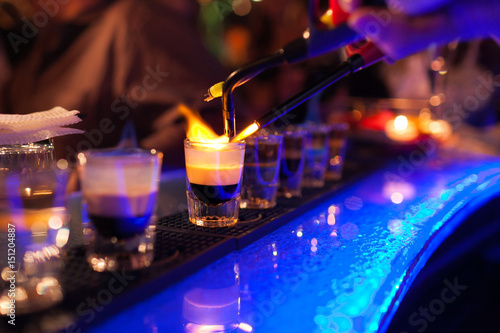 The bartender makes hot alcoholic cocktail and ignites bar. elite night club during party prepares a fiery cocktail. Fire on bar.