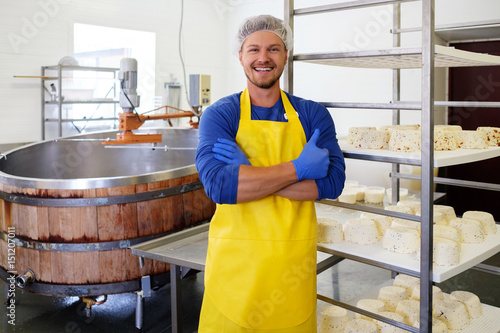 Photos Handsome cheesemaker making curd cheese in his factory.