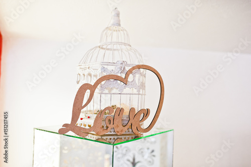 Wooden letter love at mirror cube and white decor cage on wedding reception.