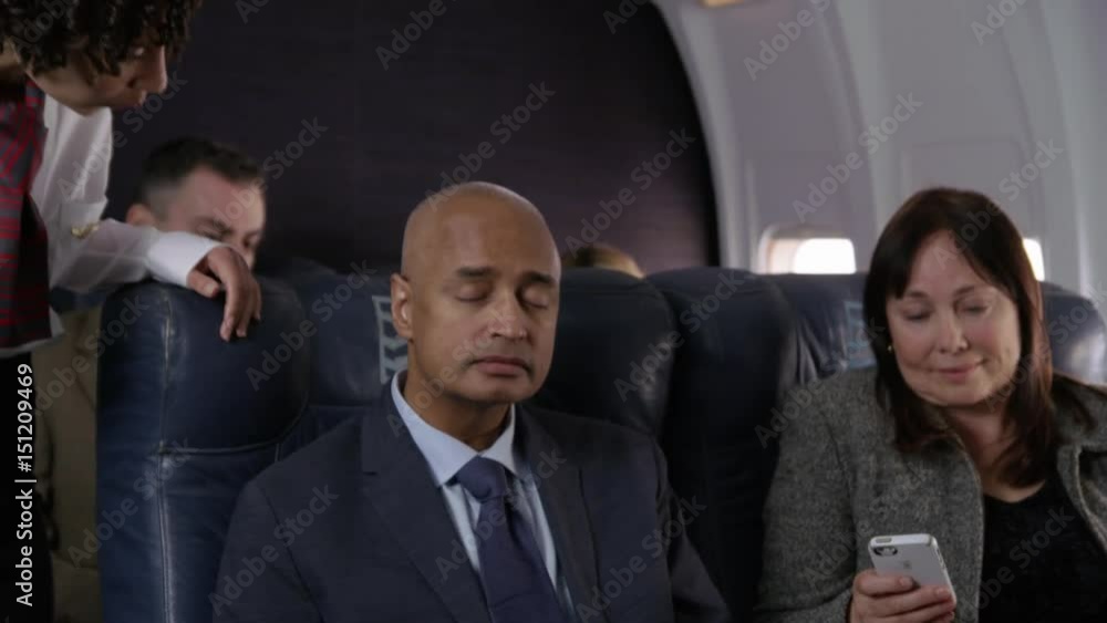 Flight attendant talking to passengers on airplane Flight attendant talking to passengers on airplane