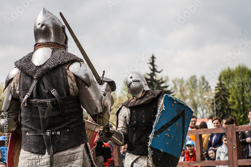 Knight tournament. The knights in the congregations are fighting in the ring. Public event in the city. Soldiers in armor of the Middle Ages.