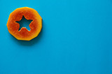 A piece of orange papaya on blue background.