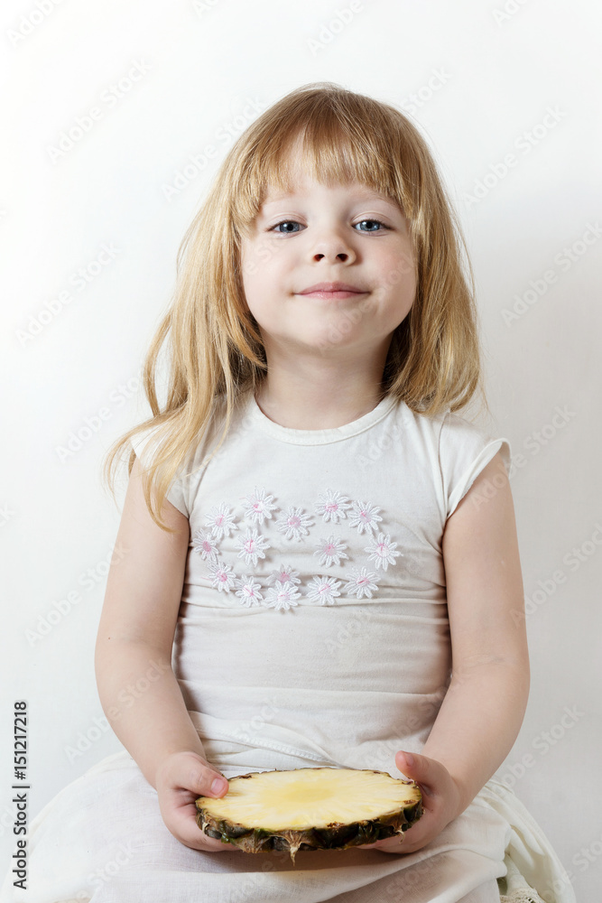 little girl holding a slice of pineapple and smiling little girl holding a slice of pineapple and smiling