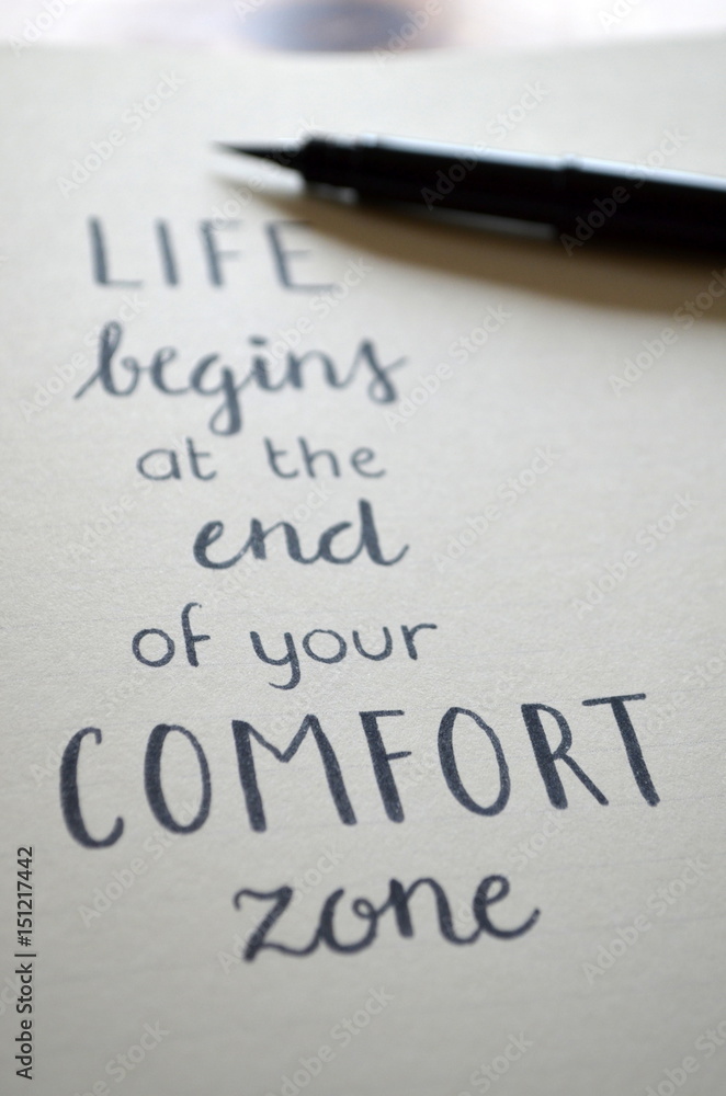 LIFE BEGINS AT THE END OF YOUR COMFORT ZONE written in brush calligraphy on notepad LIFE BEGINS AT THE END OF YOUR COMFORT ZONE written in brush calligraphy on notepad