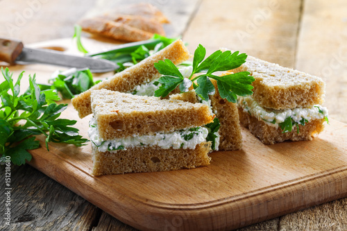 Simple cream cheese sandwiches with parsley and green onion on a table. Delicious healthy homemade snack.