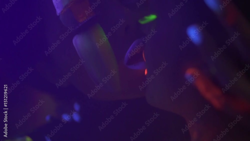 Closeup view of two beautiful girls in fluorescent clothing under UV black light petting each other and kissing Closeup view of two beautiful girls in fluorescent clothing under UV black light petting each other and kissing