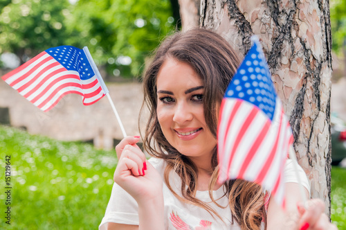 country, patriotism, independence day and people concept - happy smiling young woman in white dress with national american flag photo