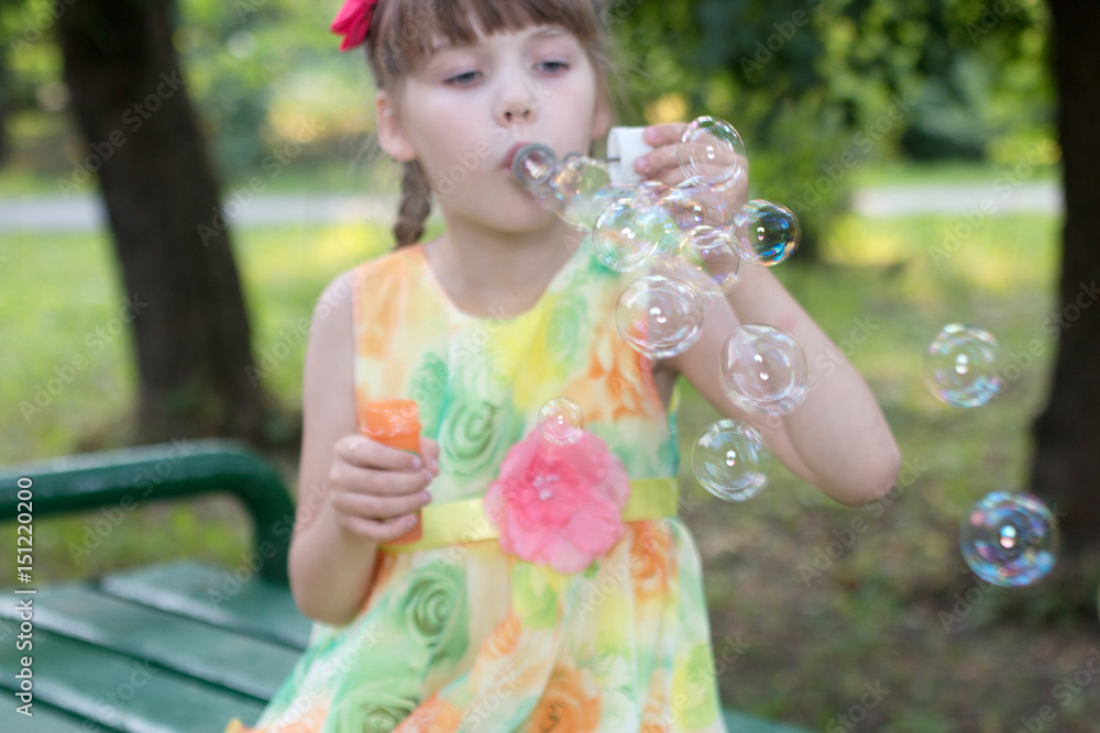 Beautiful little girl in color dress that takes lots of soap bubbles warm day, focus on bubbles Beautiful little girl in color dress that takes lots of soap bubbles warm day, focus on bubbles