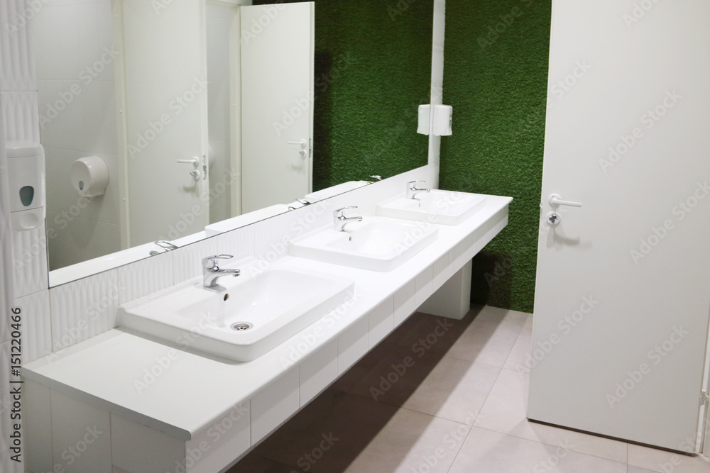 Three white sinks in toilet with big mirror and green lawn wall Three white sinks in toilet with big mirror and green lawn wall