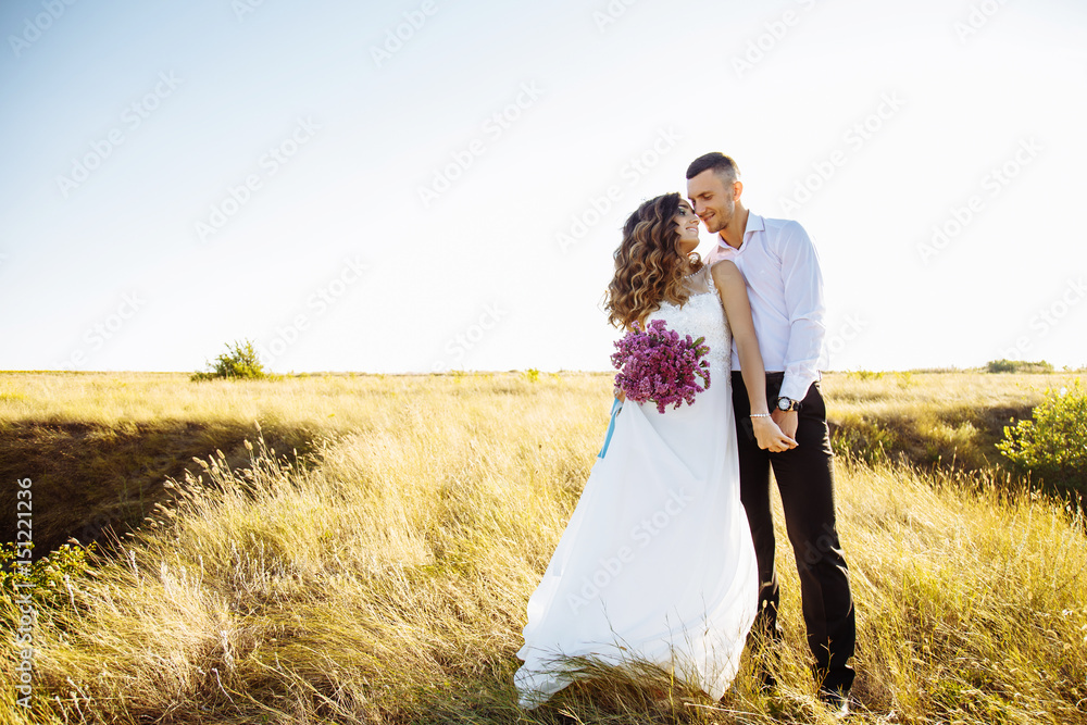 Beautiful couple in field, Lovers or newlywed posing on sunset with perfect sky Beautiful couple in field, Lovers or newlywed posing on sunset with perfect sky