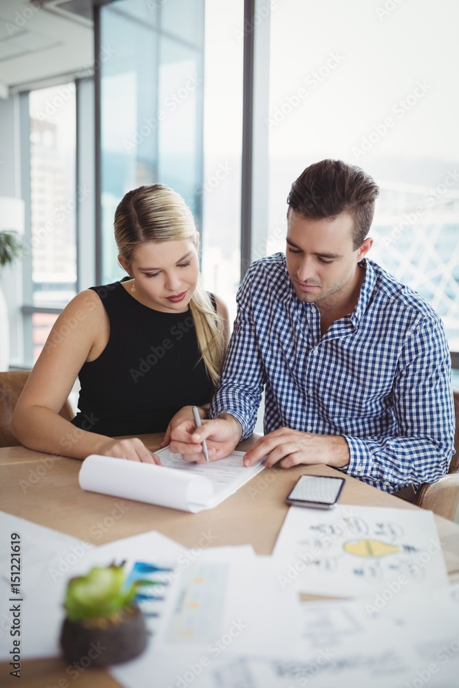 Executives discussing over paper at desk