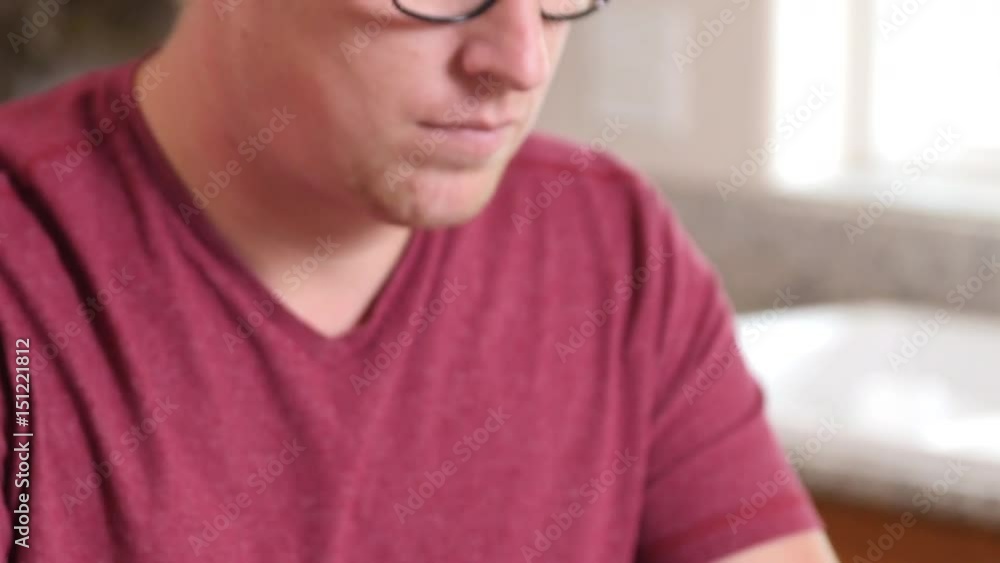 Man working on laptop computer in kitchen at home Man working on laptop computer in kitchen at home
