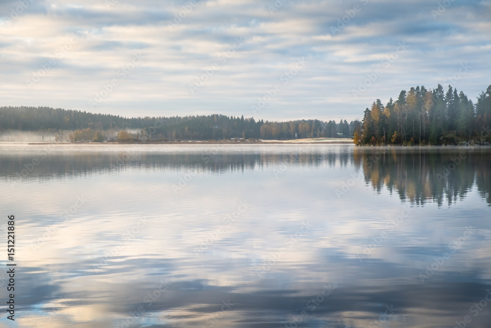 Scenic landscape with peaceful lake and fog at autumn morning