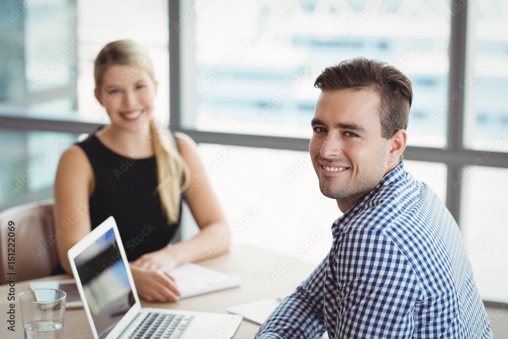 Portrait of smiling executives sitting at desk Portrait of smiling executives sitting at desk