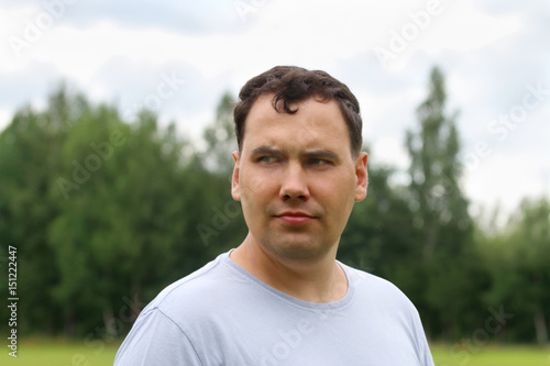 Young man looks away outdoor at summer day, close up