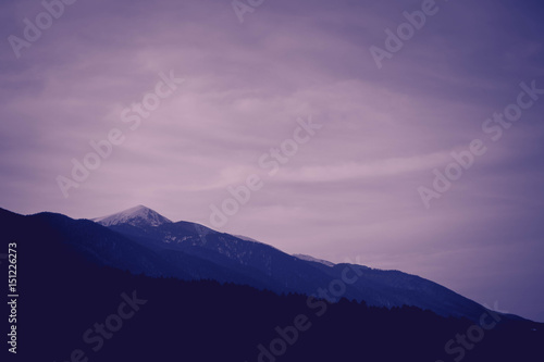 Photo depicting a beautiful moody frosty landscape European alpine mountains with snow peaks on a blue sky background. © alicefoxartbox