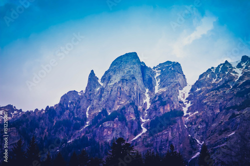 Photo depicting a beautiful moody frosty mountainous landscape. European alpine mountains with snow peaks on a blue sky background