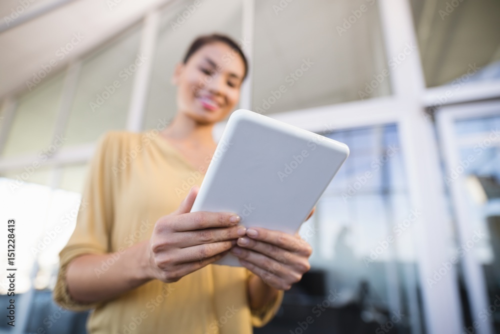 Low angle view of smiling businesswoman using tablet in office Low angle view of smiling businesswoman using tablet in office