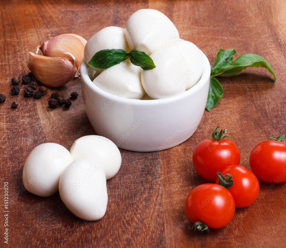 Cherry mozzarella in bowl, cherry tomatoes,fresh basil, garlic and pepper on wooden board. Cherry mozzarella in bowl, cherry tomatoes,fresh basil, garlic and pepper on wooden board.