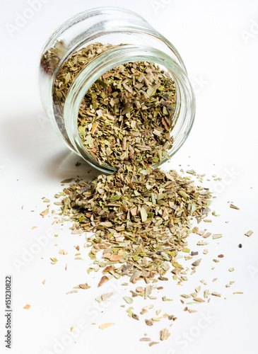Oregano in glass jar. Heap. Isolated on white.
