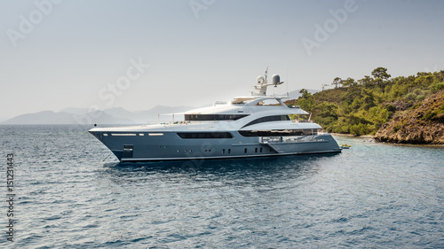 A large private luxurious modern private yacht around the island on a background of the sky © deineka