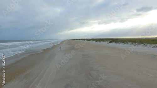 Woman in white walking along Masonboro Island beach wide aerial fall photo