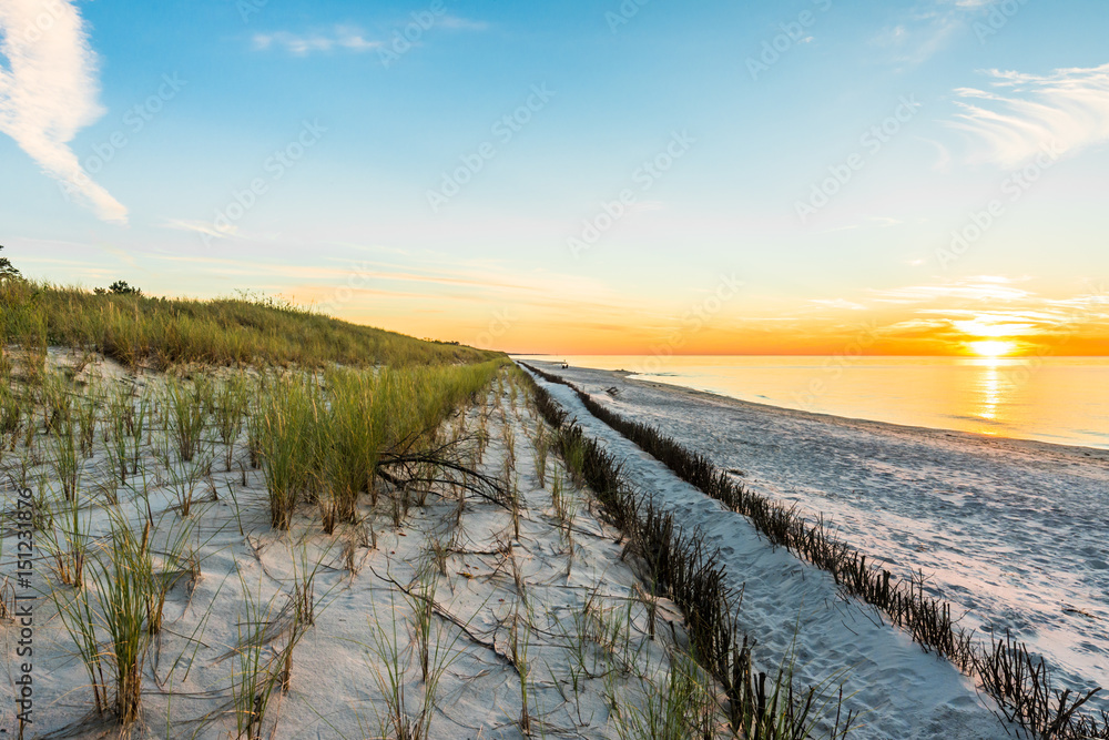 Fototapeta premium Sandy beach and sunset sky with golden sun shining on white sand