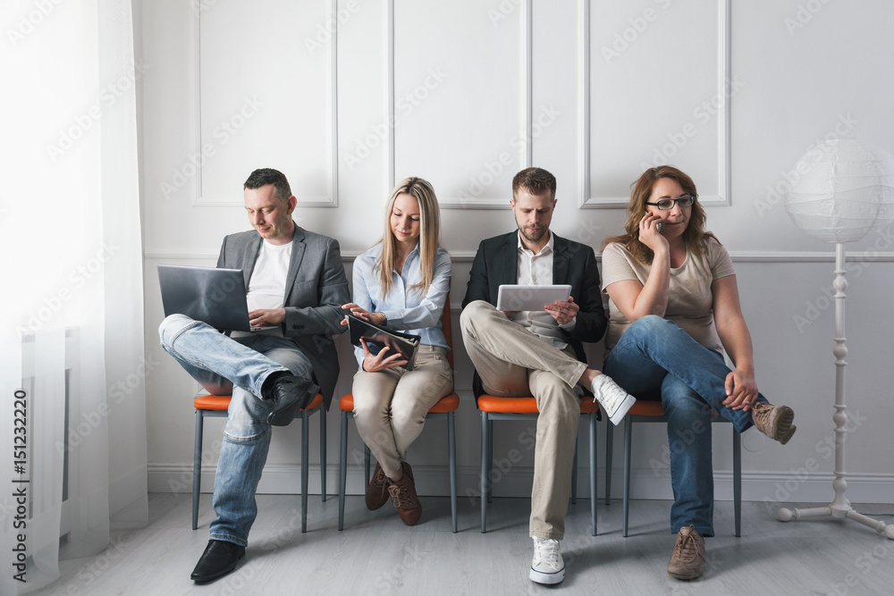 Fototapeta premium Group of creative people sitting on chairs in waiting room