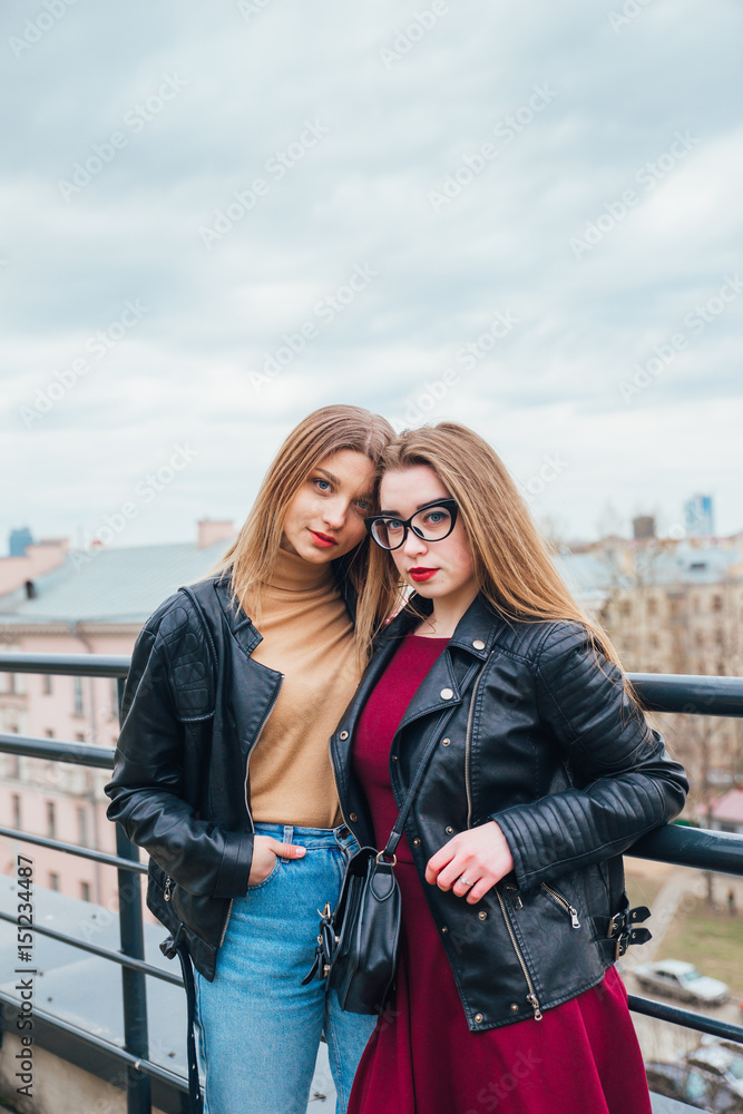 couple of women together in cityscape . Two joyful beautiful fashionable girls on roof . Beautiful city view