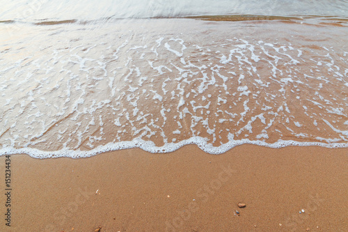 Soft white wave of sea on sandy beach used as Background.