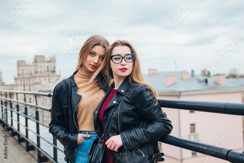 couple of women together in cityscape . Two joyful beautiful fashionable girls on roof . Beautiful city view © Elena Kratovich