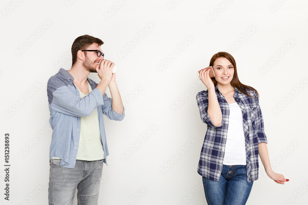 Young casual couple talking through tin can phone Young casual couple talking through tin can phone