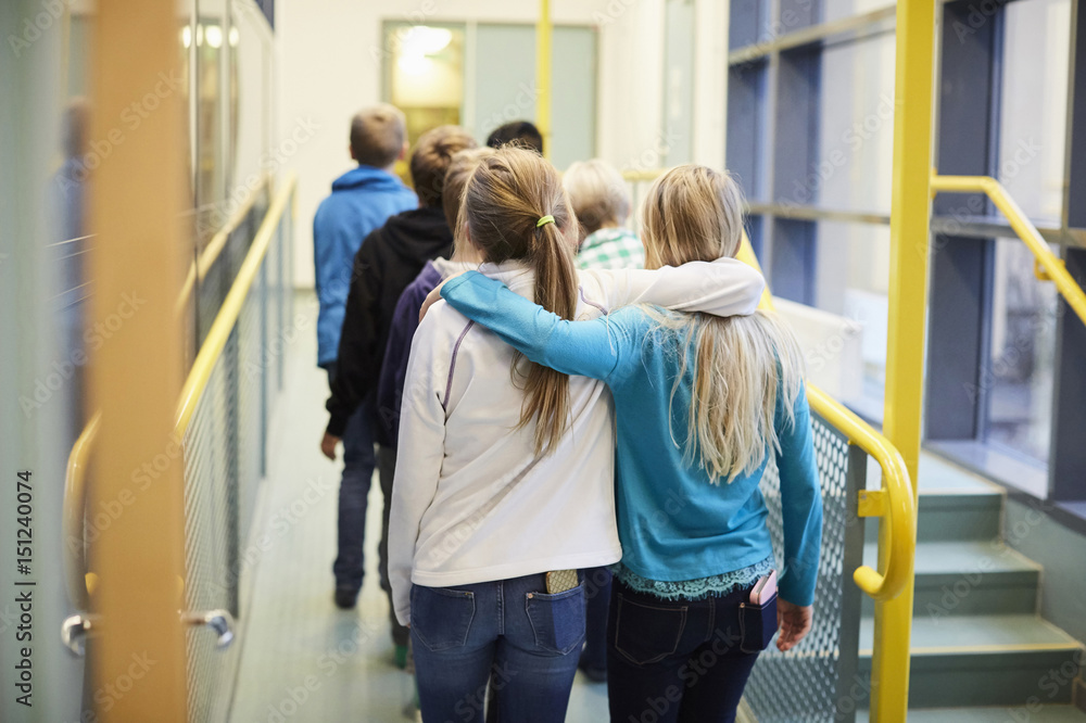 Rear view of girls walking arm around in school corridor Rear view of girls walking arm around in school corridor
