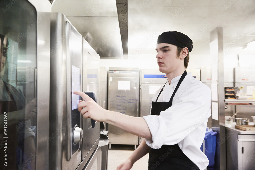 Male chef student operating microwave oven at cooking school Male chef student operating microwave oven at cooking school