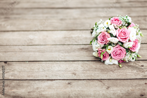 A bridal bouquet of a bride from white and pink roses lies on a wooden background, horizontally
