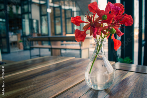 Summer flowers in a glass vase placed on a wooden table. photo