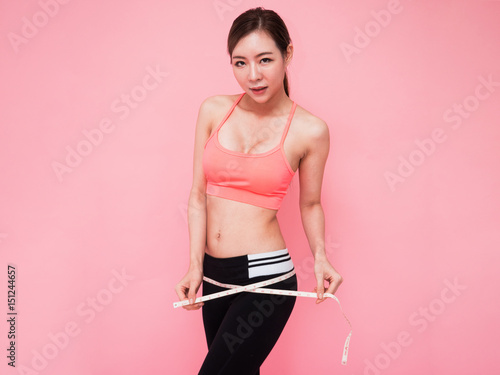 Slim young Asia woman measuring her leg with a tape measure, close up © Sataporn