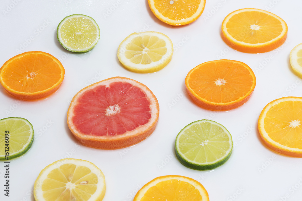 cut citrus slices orange, grapefruit, lemon, lime, tangerine on a white background filled with water
