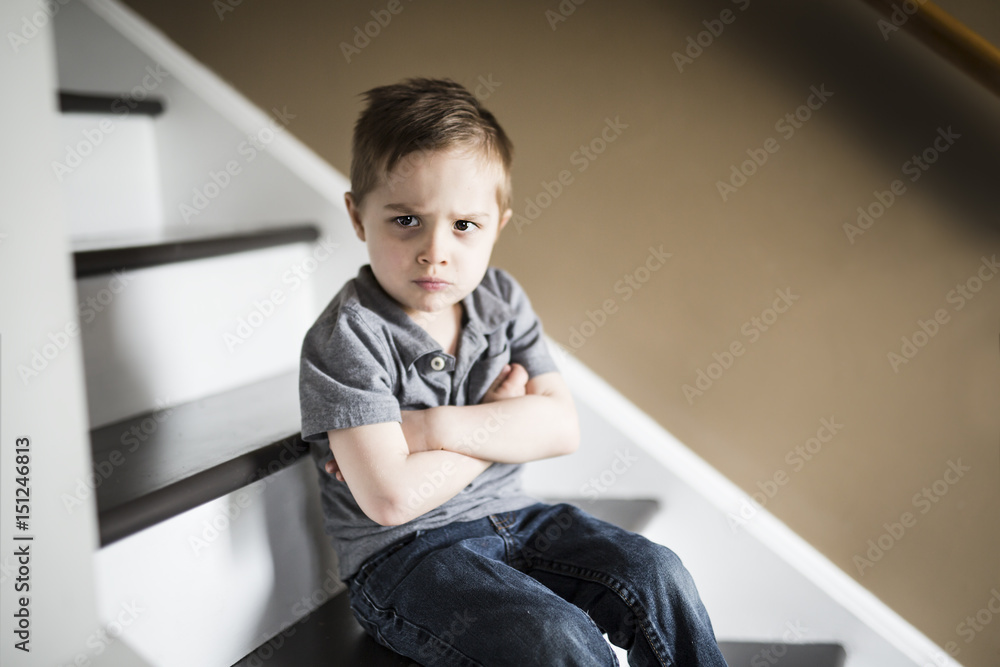 one sad little boy sitting on the stairs in house at the day time. one sad little boy sitting on the stairs in house at the day time.