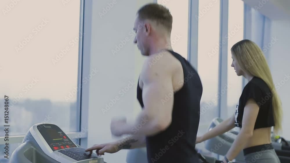 A man and a girl are training on a treadmill in a fitness club A man and a girl are training on a treadmill in a fitness club