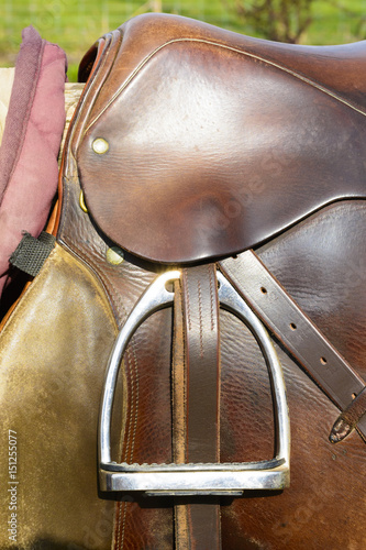 Closeup leather cowboy saddles hanging on the railing © karelpesorna