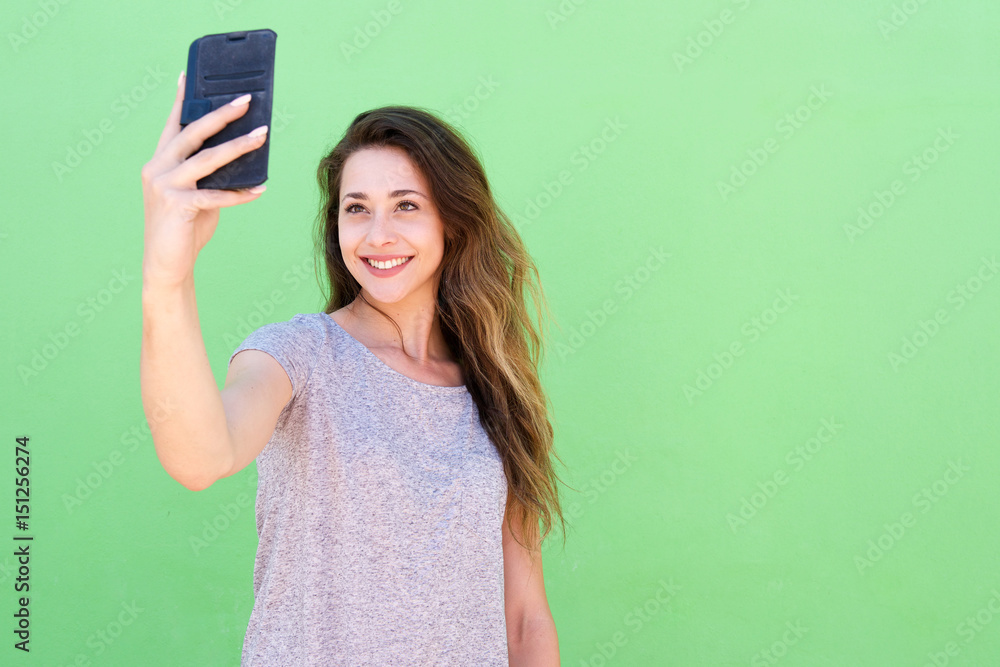 young woman taking a selfie and smiling against green background young woman taking a selfie and smiling against green background