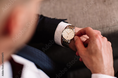 watch with white dial on the hand of a man in a white shirt